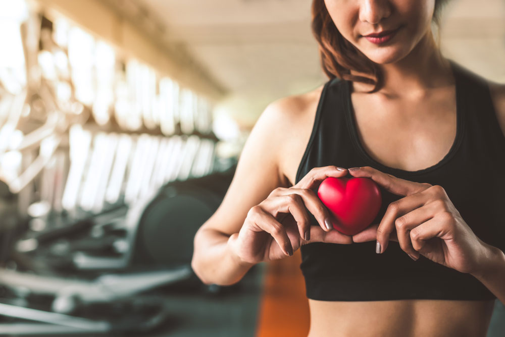 Woman in gym holding a wooden red heart in her hands